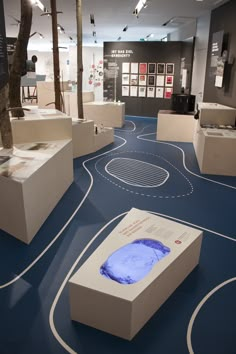 an exhibit room with blue flooring and white boxes