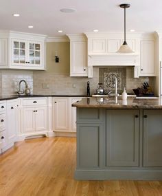 a large kitchen with white cabinets and wood floors