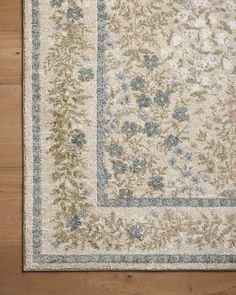 an area rug with blue and green flowers on the side, sitting on top of a wooden floor