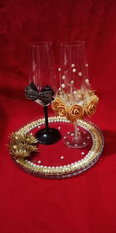 two wine glasses sitting on top of a glass platter with gold trimmings