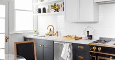 a kitchen with black and white cabinets, marble counter tops and gold trimmings