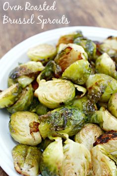 brussel sprouts on a white plate sitting on top of a wooden table