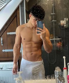 a shirtless man taking a selfie in front of a mirror with his cell phone