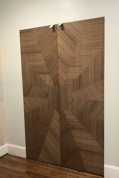 a large wooden door in the corner of a room with hard wood flooring and white walls