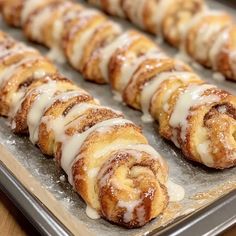 cinnamon rolls are lined up on a baking sheet