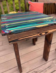 a wooden table sitting on top of a wooden floor next to a red and blue pillow