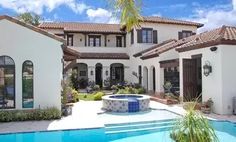 a large white house with a pool in the front yard and palm trees around it