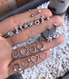 a person holding several different types of rings and piercings on their fingers in front of the camera