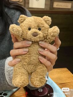 a woman holding a brown teddy bear in her hands