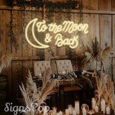 a sign that says to the moon and back in front of some chairs with candles