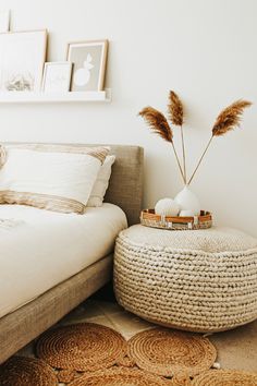 a bed with white sheets and pillows in a bedroom next to a basket on the floor