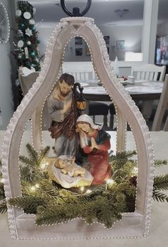 a nativity scene is displayed in the center of a table with christmas lights on it