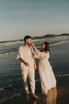 a man and woman are walking on the beach