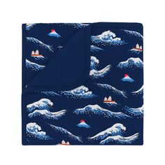 a blue blanket with an image of waves and boats on the ocean in front of it