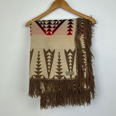 a brown and white blanket hanging on a wooden hanger next to a white wall