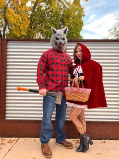 a man and woman dressed up in costumes standing next to each other, one holding a bat