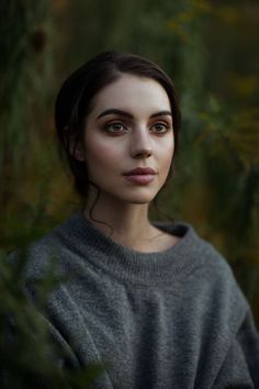 a black and white photo of a woman in a sweater looking at the camera with an intense look on her face