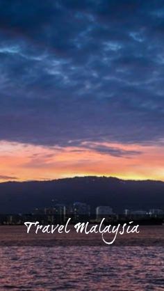 the sky is purple and blue as it sits over water with mountains in the background