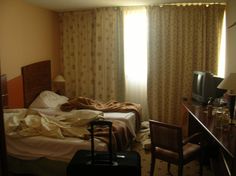 a hotel room with a bed, desk and luggage