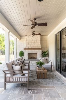 an outdoor living area with couches and ceiling fans