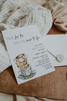 a card with a tea cup and saucer on it next to a white envelope