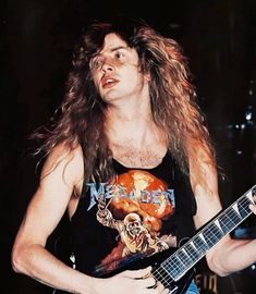 a man with long hair playing an electric guitar