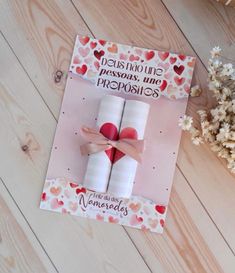 a card with two rolled up candles on top of it and a bouquet of flowers in the background