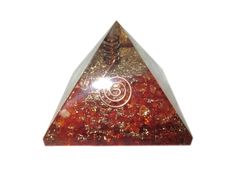 a triangle shaped piece of red and gold colored rock with a spiral design on it