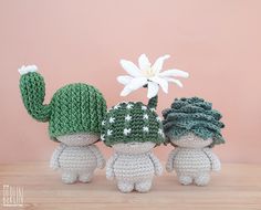 three crocheted dolls with hats and flowers in front of a pink background