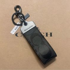 a black leather keychain with a white tag on it sitting on top of a cardboard box