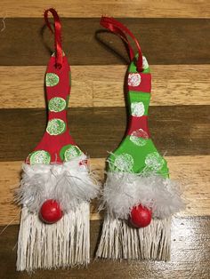 two red and green christmas ornaments with white feathers on them sitting on a wooden floor