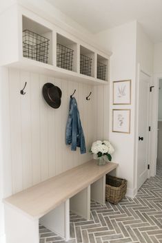 a coat rack with hats and coats hanging on it next to a bench in a hallway