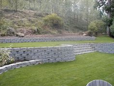 an outdoor seating area with stone walls and green grass