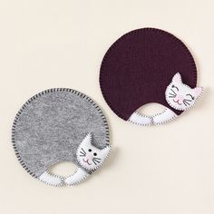 two pieces of felt with cats on them, one is purple and the other is grey