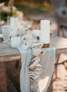 the table is set with white candles and napkins on it, along with other items