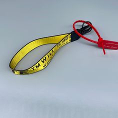 a pair of yellow lanyards with black handles on a gray background, one has a red handle