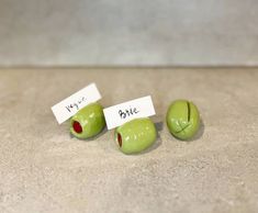 three green apples with faces and words on them sitting on the floor next to each other