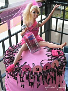 a barbie doll sitting on top of a pink cake