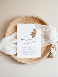 a baby announcement card on top of a wooden bowl with white yarn and a crochet doily