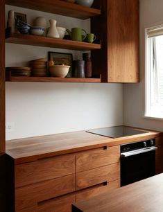 a kitchen with wooden cabinets and shelves filled with dishes on top of the counter tops