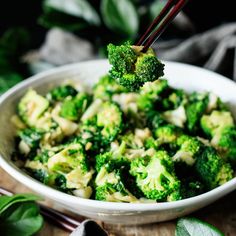 a bowl filled with broccoli on top of a wooden table