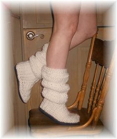 a woman's legs in white crocheted boots sitting on a wooden chair