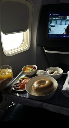 an airplane tray with food on it and a tv in the back ground behind it