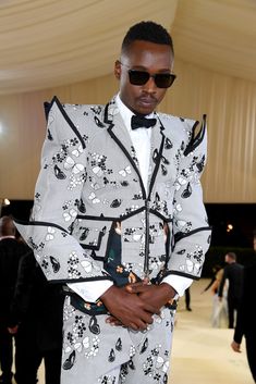 a man in a suit and sunglasses standing on a runway