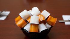 an arrangement of candies in a black bowl on a table with utensils