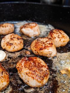 seared scallops cooking in a skillet with oil on the stove top