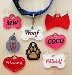 dog tags with name and paw prints on them are hanging from a blue cord that is attached to a wooden surface