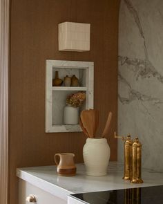 a kitchen with marble counter tops and gold accents on the wall, along with white cabinets