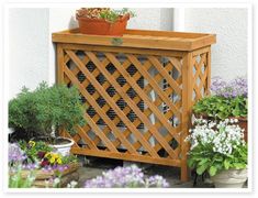 a wooden planter sitting on top of a patio next to potted plants and flowers