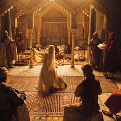 a group of people dressed in medieval clothing sitting on the floor and looking at each other